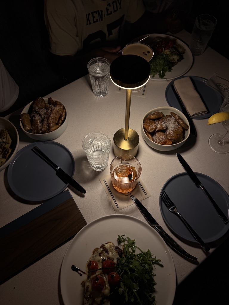 Warm overhead dinner table under a lamp, shared plates and glasses