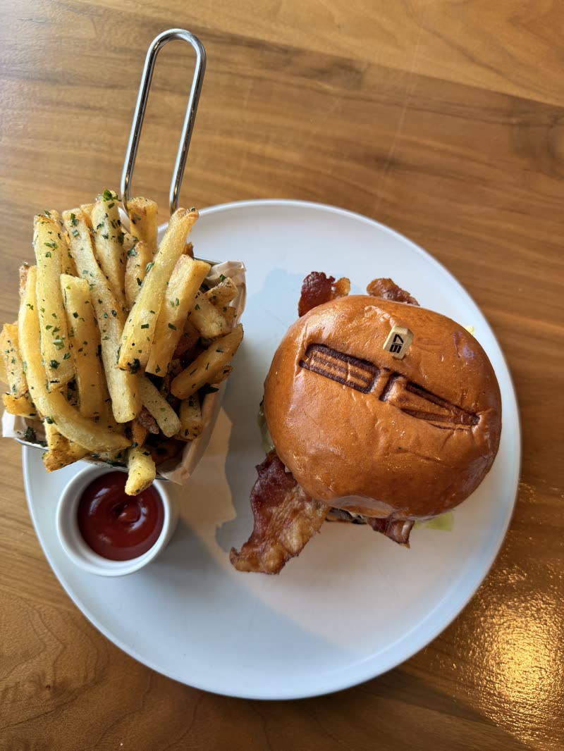 Gourmet burger with fries and ketchup held over the plate