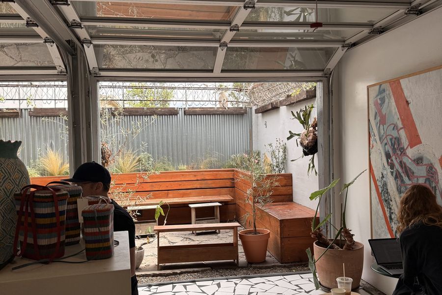 Bright indoor–outdoor cafe courtyard with seating and open garage doors