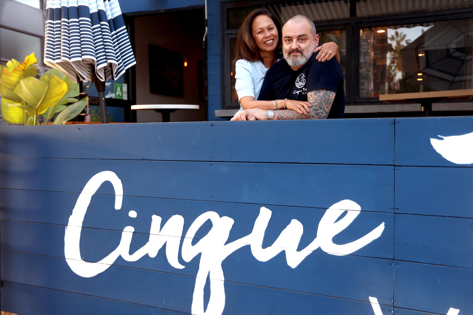 Cinque Terre West owners at the blue patio wall with Cinque signage, Venice