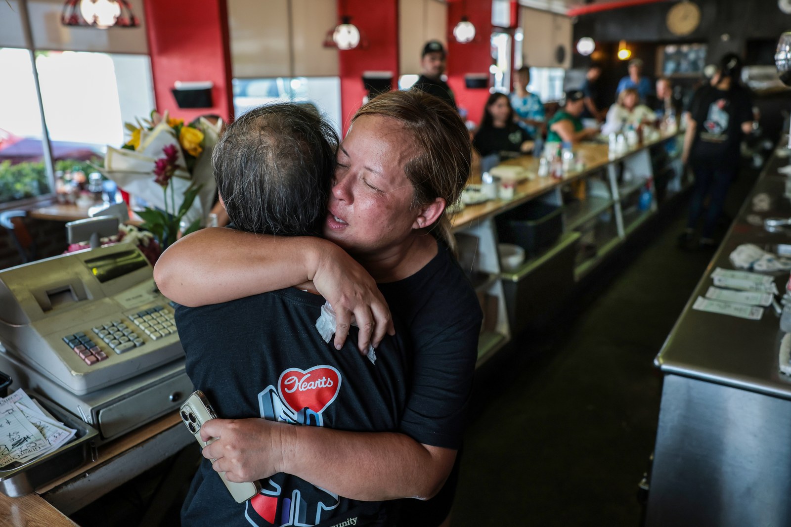 Heart’s Coffee Shop diner counter with staff embracing; Heart’s logo on shirt, Lake Balboa