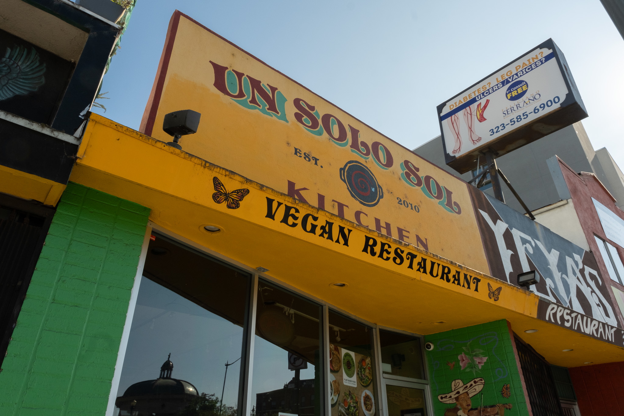 Un Solo Sol Kitchen yellow and green vegan restaurant storefront on 1st Street near Mariachi Plaza, Boyle Heights