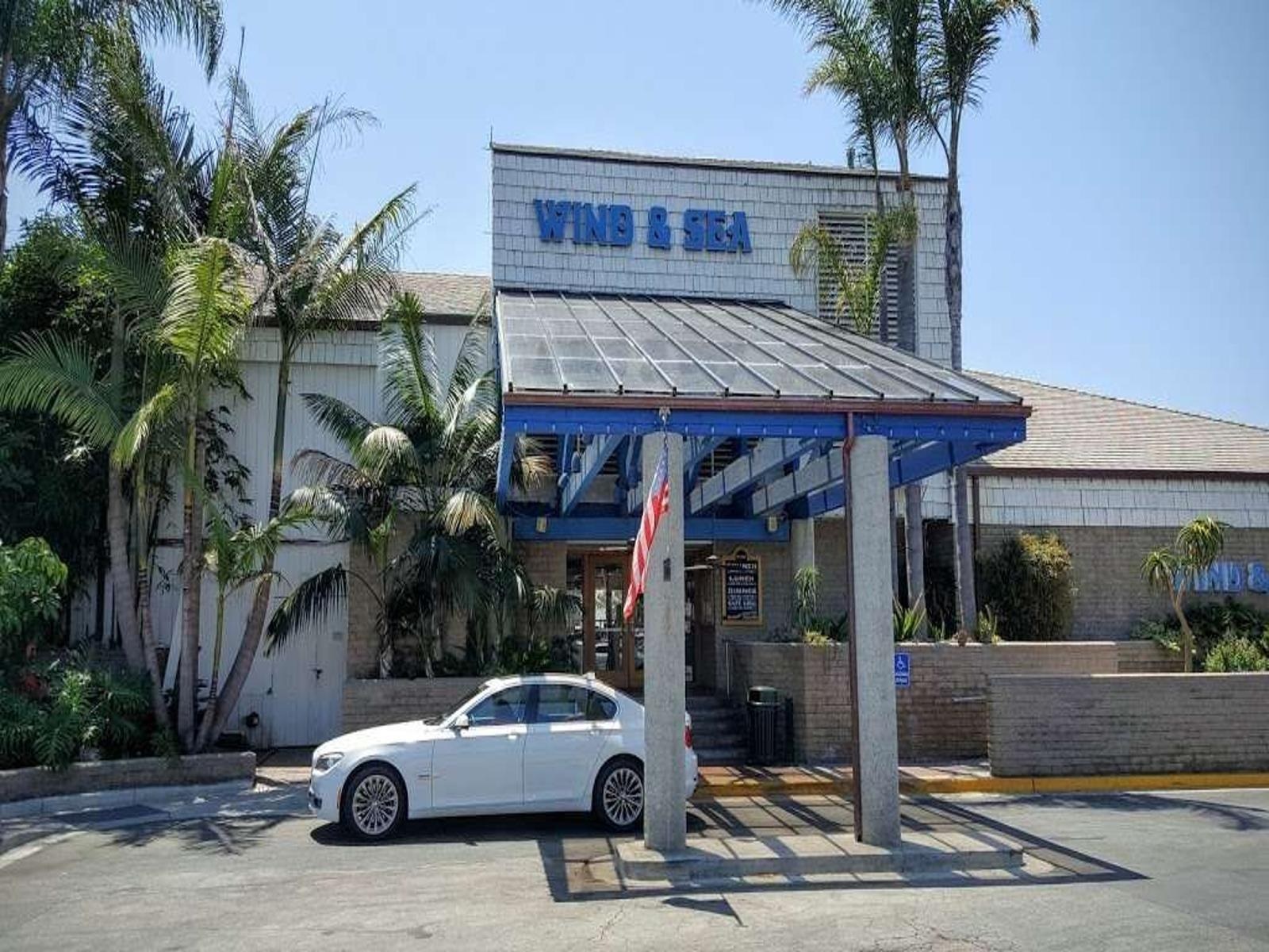 Wind & Sea Restaurant exterior with blue lettering and palm trees, Dana Point Harbor